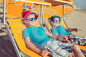 Little boys showing away in deckchair on beach