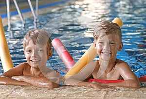 Little boys with swimming noodles in pool