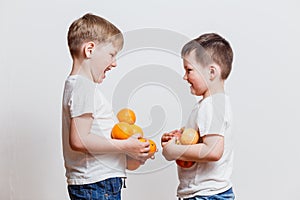 Little boys in white t-shirts with fruit in hand