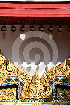 A little brass bells hanging and wooden Carving on entrance door of Thai Pattern on a Church of Temple.