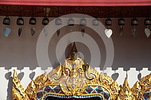 A little brass bells hanging and wooden Carving on entrance door of Thai Pattern on a Church of Temple.