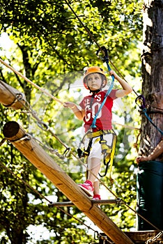 Little brave caucasian girl at outdoor treetop climbing adventure park
