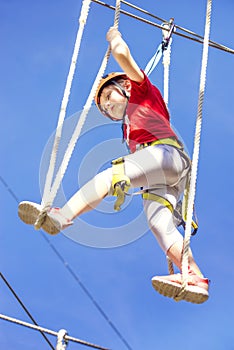 Little brave caucasian girl at outdoor treetop climbing adventure park