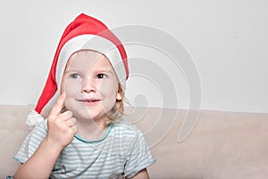 Little bright girl with a beautiful smile in a santaclaus cap photo