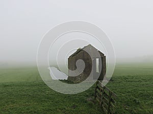 Little broken house in a misty landscape in the meadow