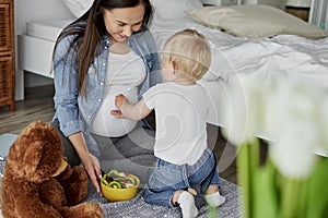 Little brother feeding with fruits his future sibling