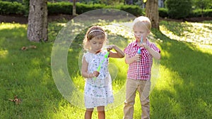 Little brother and sister blowing bubbles on the grass in the Park.