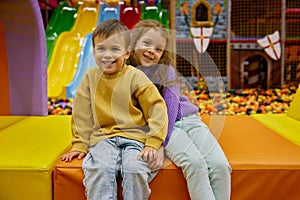 Little brother and sister cuddling together while rest at game center