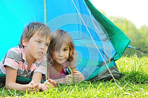 Little brother and sister lying inside tent