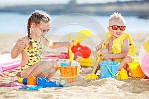 Little brother and sister playing on the beach in the sand