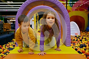 Little brother and sister positive children playing in indoor park