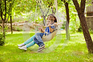 The little brother and sister are resting sitting in a hammock