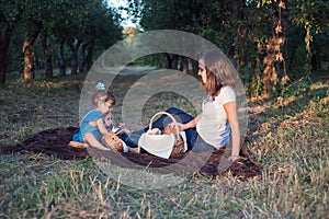 Little brother and sister sit in a row at a family picnic. Time for family