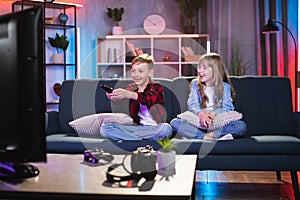 Little brother and sister sitting on couch and watching TV