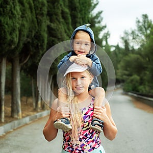 Little brother of sitting on his sister`s neck, happy children