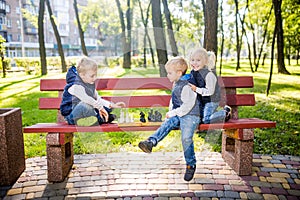 Little brothers playing chess with sister on bench in park. Children intelligence development. Family leisure time. Kids playing