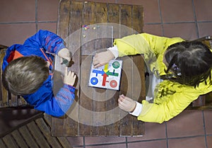 Little brothers playing Parchis over wooden vintage table photo