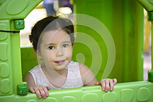 Little brown hair girl smiling through the window of kids playhouse