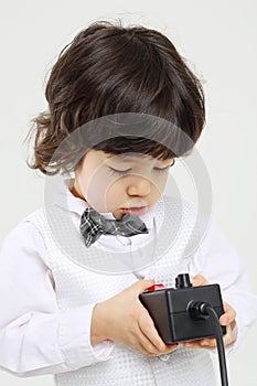 Little brunet boy holds black control console on