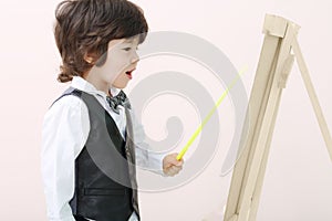 Little brunet boy with yellow pointer stands