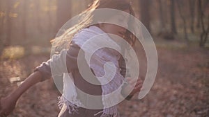 Little brunette girl with a bright scarf and long hair. Scared child is running in rush through the mysterious forest