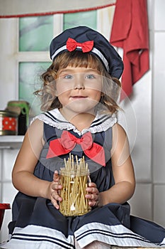 Little brunette girl with curls in a marine suit - dress  in the kitchen