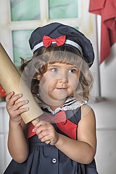 Little brunette girl with curls in a marine suit - dress  in the kitchen