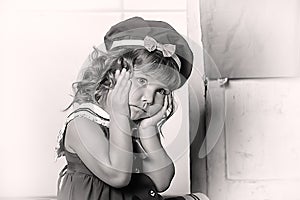 Little brunette girl with curls in a marine suit - dress  in the kitchen