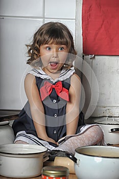 Little brunette girl with curls in a marine suit - dress  in the kitchen