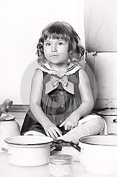 Little brunette girl with curls in a marine suit - dress  in the kitchen