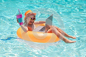 Little businessman working on tropical beach. Kid boy relaxing in the pool, using laptop computer in summer water. Child