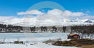 Little cabin in the wilderness towards icy lake