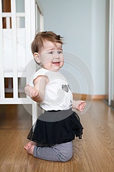 Little capricious child standing on floor of domestic room, screaming and crying. Girl behaves badly