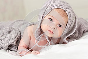 Little Caucasian baby baby 3 months in a gray knitted hat. Portrait of a small child, close-up soft focus