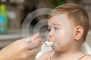 Little Caucasian baby boy with hand close his mouth no eat his food. Kid with dirty messy face sitting in high chair