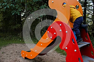 Little caucasian boy climbing on a slide, outdoor playground