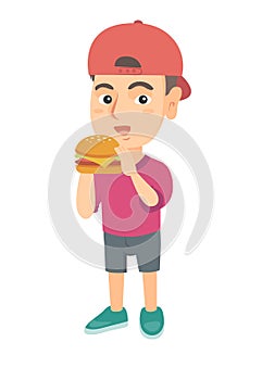 Little caucasian boy eating a hamburger.