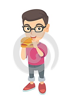 Little caucasian boy eating a hamburger.