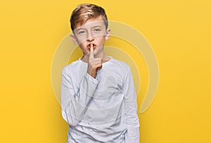 Little caucasian boy kid wearing casual clothes asking to be quiet with finger on lips