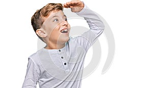 Little caucasian boy kid wearing casual clothes very happy and smiling looking far away with hand over head