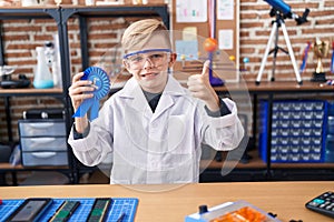 Little caucasian boy at school scientist laboratory winning first prize smiling happy and positive, thumb up doing excellent and