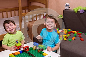 Little caucasian child playing with lots of colorful plastic blocks indoor. Kid boy wearing shirt and having fun building creating