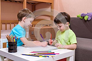 Little caucasian child playing with lots of colorful plastic blocks indoor. Kid boy wearing shirt and having fun building creating