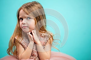 Little Caucasian female child in pink dress with naughty and resentful face expression.