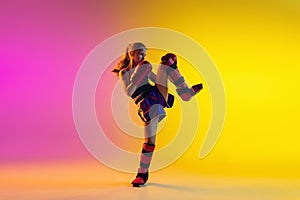 Little caucasian female kick boxer training on gradient background in neon light, active and expressive