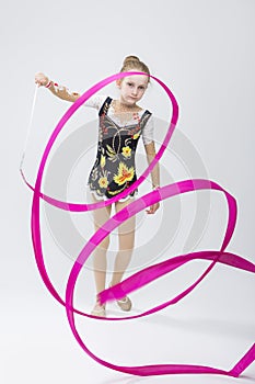 Little Caucasian Female Rhythmic Gymnast In Professional Competitive Suit Doing Artistic Ribbon Spirals
