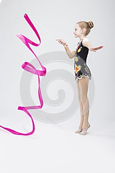 Little Caucasian Female Rhythmic Gymnast In Professional Competitive Suit Doing Artistic Ribbon Spirals Exercises