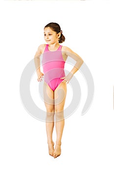 Little caucasian female 8 years old girl in pink swimmwear jumping on white background.