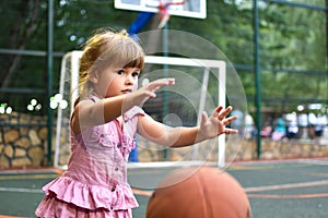 Little caucasian girl with ball on outdoor playground. children`s sports for health.