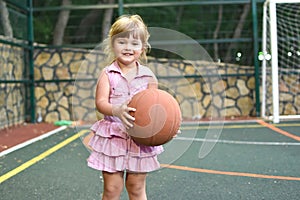 Little caucasian girl with ball on outdoor playground. children`s sports for health.